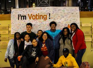 Students of color gather around a signed poster that reads: I'm Voting!